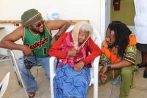 International reggae artistes (l-r) Duane Stephenson and Droop Lion show fascination with103-year-old Flambouyant Nursing Home resident Ms. Jane Canning 