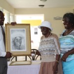 St. Thomas’ Parish’s eldest resident Alice Nisbett accepts her self portrait from the Permanent Secretary in the Ministry of Social Development Keith Glasgow on United Nations International Day of Older Persons on October 1, 2013, while her daughter Muriel St. Jean looks on. 