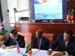 Minister of Information Technology, the Hon. Glen Phillip (right) and Taiwan’s Resident Ambassador, His Excellency Mr. Miguel Tsao (left) sign the Agreement in the presence of St. Kitts and Nevis’ Prime Minister the Right Hon. Dr. Denzil L. Douglas (c).