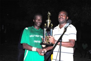  Area Parliamentary Representative the Hon Shawn Richards presents the National Caribbean Insurance Ltd Sandy Point Community Football League trophy to Captain Charles Thomas of the Glen 'Ghost' Phillip Half Way Tree United FC.