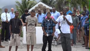 Head of the Nevis Turtle Group Lemuel Pemberton (front row left) delivering remarks at the release of sea turtle Millie on the beach outside the Four Seasons Resort on Nevis on July 13, 2015 praising young volunteers in his group (l-r) Stedroy Sturge and brothers Jaleel and Jevaunito Huggins 