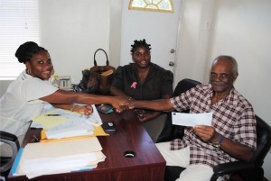 Mr Fredrick Robins-Doras receives his cheque from SWRF Officer Ms Diana Duncan. Looking on is SWRF Officer Thyra Gumbs.