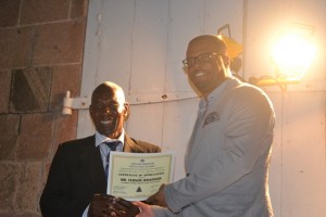 Minister of Social Development on Nevis Hon. Mark Brantley presents honouree Vernon Wilkinson of the St. Thomas Parish with a certificate of appreciation at the annual Charlestown Christmas Tree lighting Ceremony on December 02, 2015, for his outstanding contribution to the community